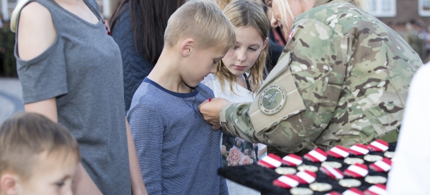 Kvindelig soldat uddeler æresmedaljer til små børn