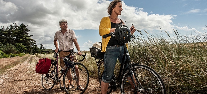 Middelaldrende man og kvinde står ved deres cykler og nyder udsigt over marker