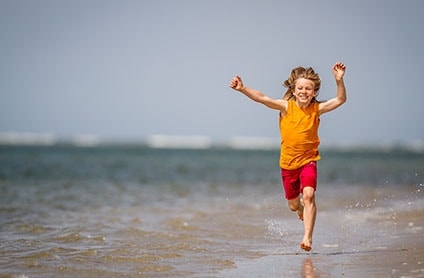 Dreng løber med armene i vejret ved vesterhavet