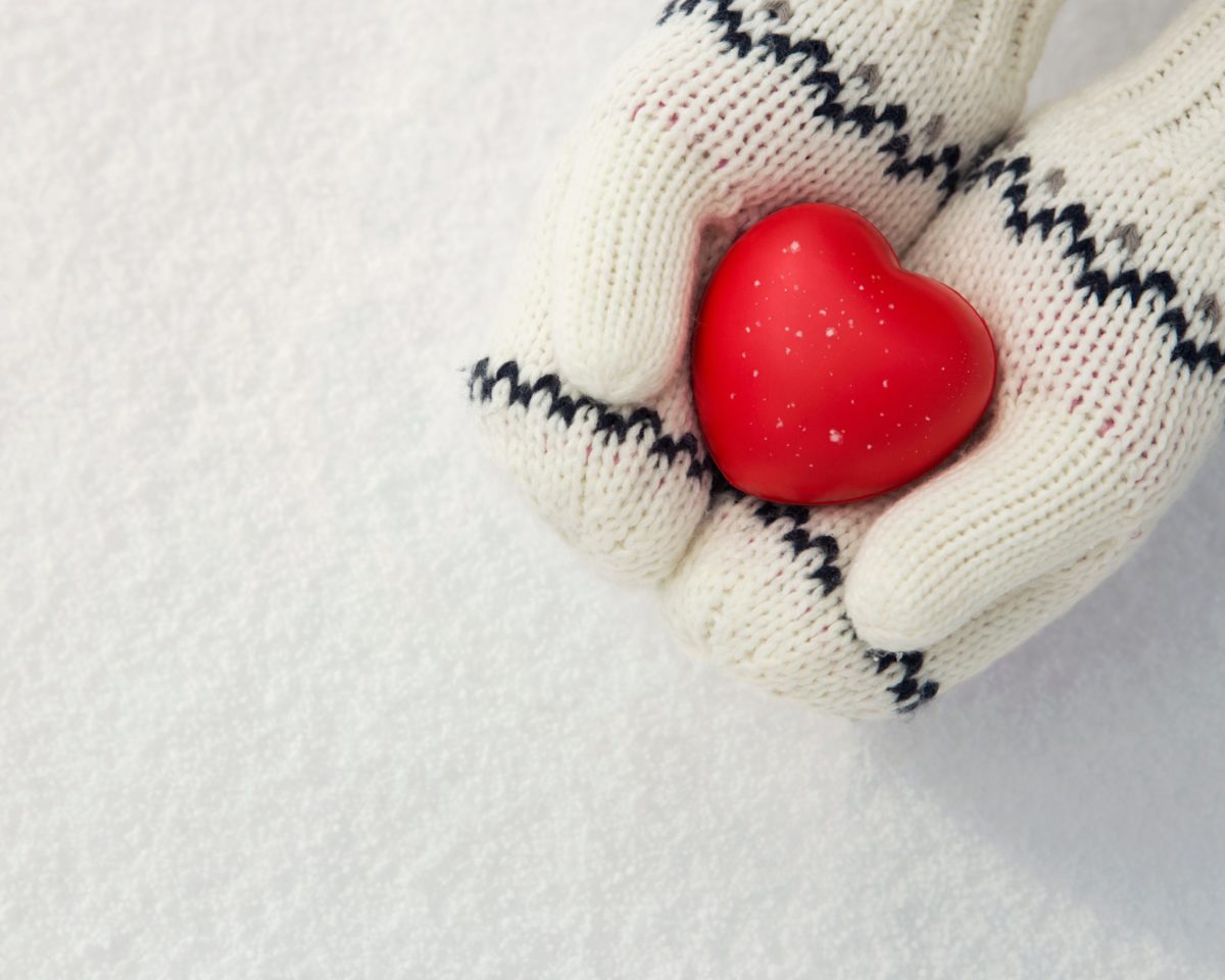 Winter background, close up of little girls hands holding red ru