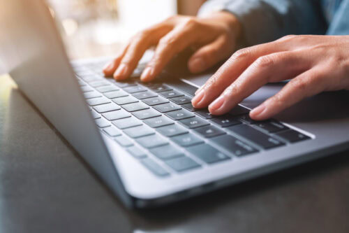 Closeup image of a woman working and typing on laptop computer o